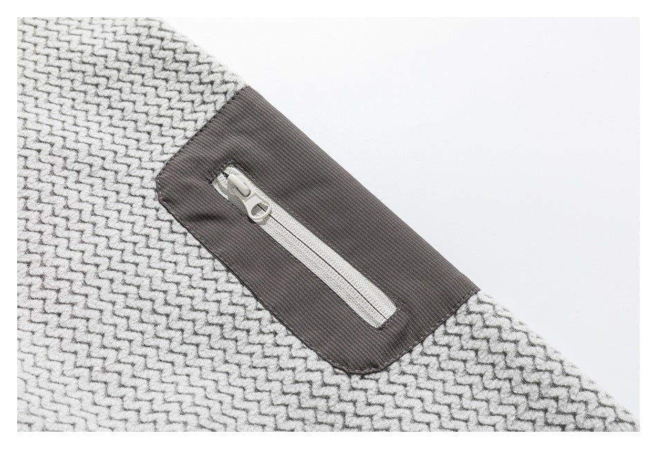 Close-up of a light gray patterned jacket with a zip pocket on a dark gray panel.