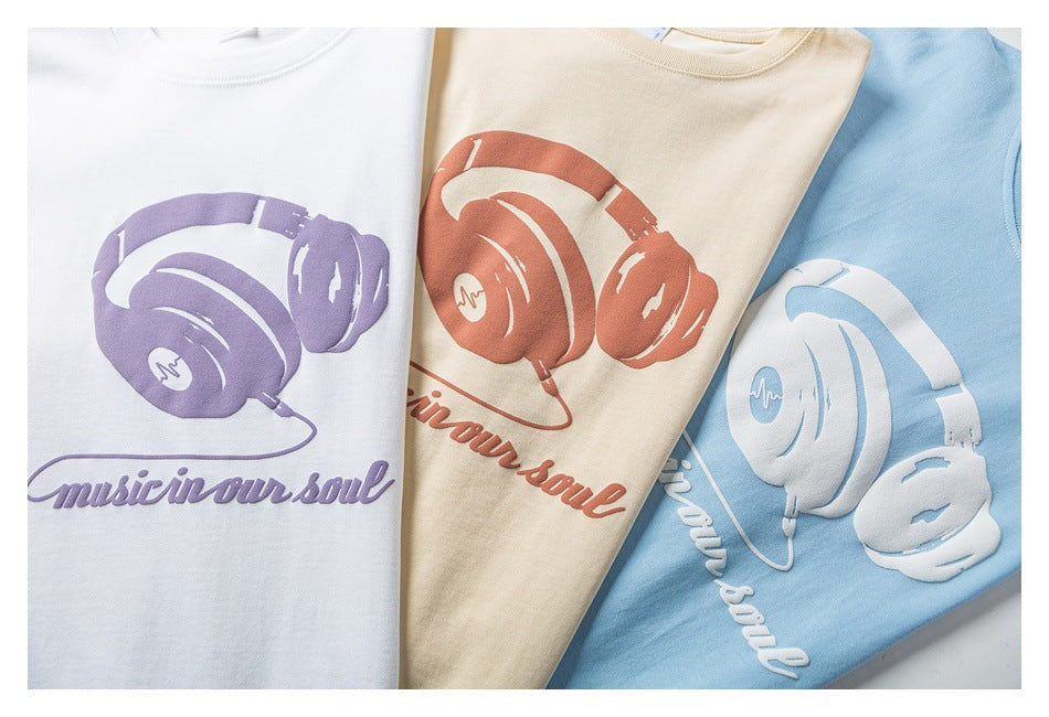 Three T-shirts in white, beige, and light blue, each with a headphone graphic and “Music in our soul” text.