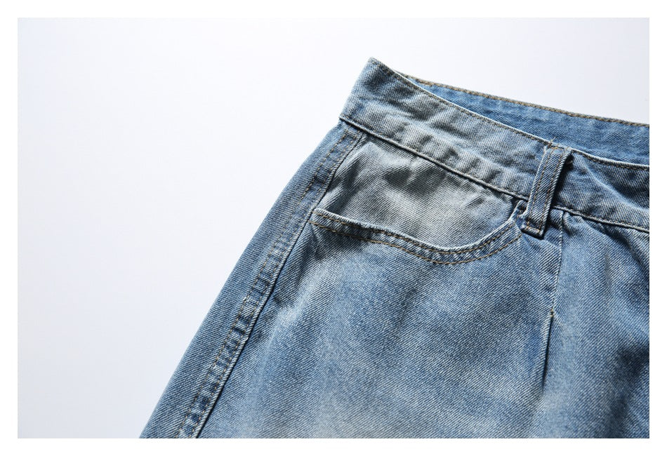 Close-up of light blue washed denim shorts showing the waistband, belt loop, and front pocket.