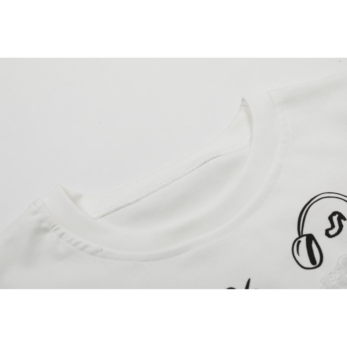 Close-up of a white T-shirt's ribbed crew neckline and part of its black music-themed print.