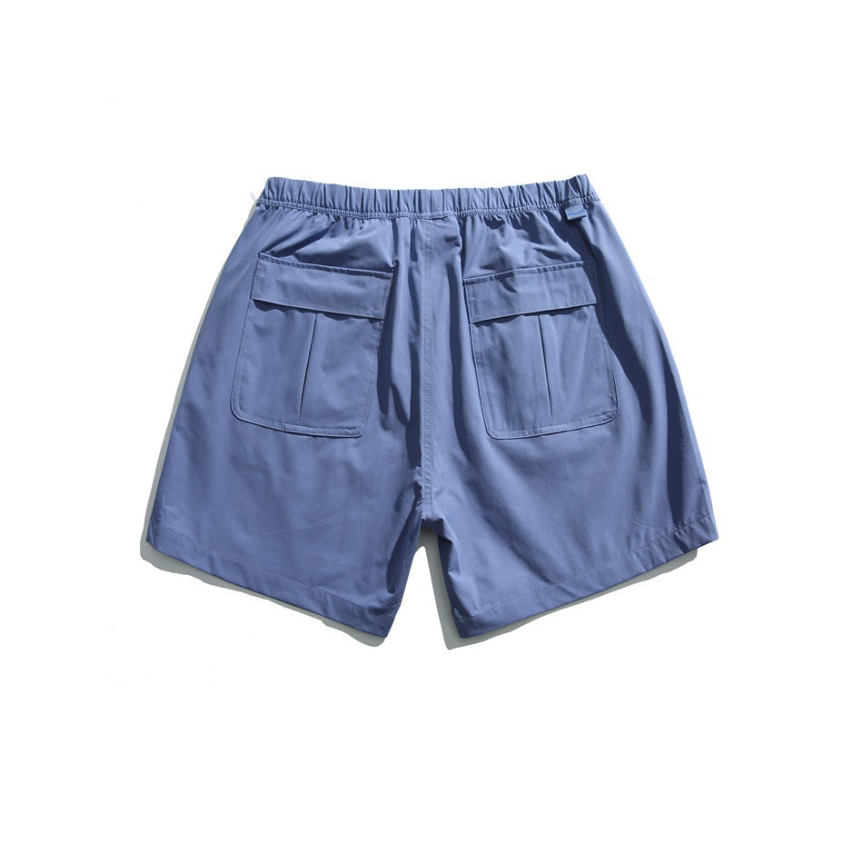 Back of blue shorts with an elastic waist and two large flap pockets.