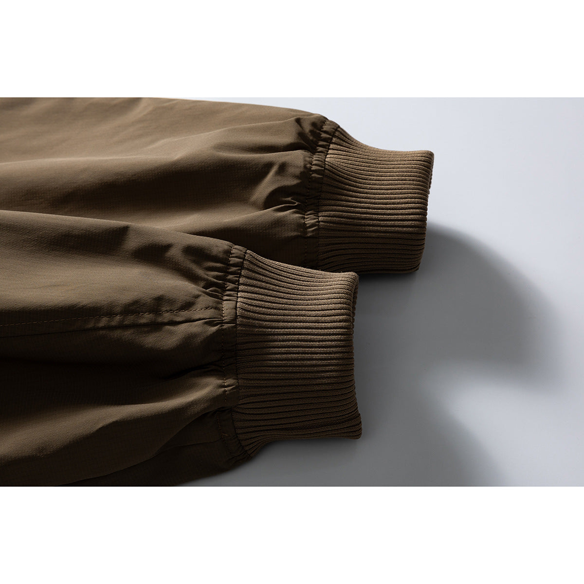 Close-up of two brown jacket sleeves with wide ribbed cuffs.