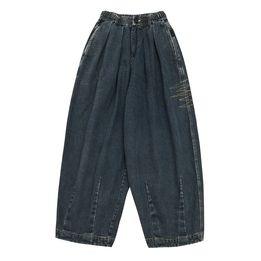 Flat-lay front of dark blue washed denim wide-leg jeans with elastic waist, pleats and gold side embroidery