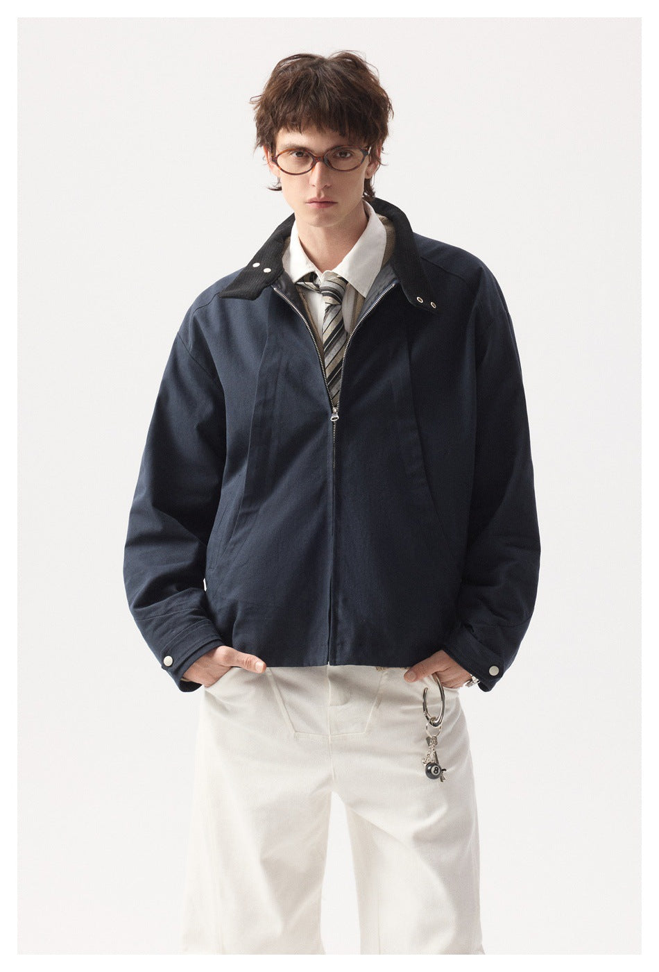 Front view of a model wearing an open navy zip jacket with a wide collar over a white shirt and striped tie.