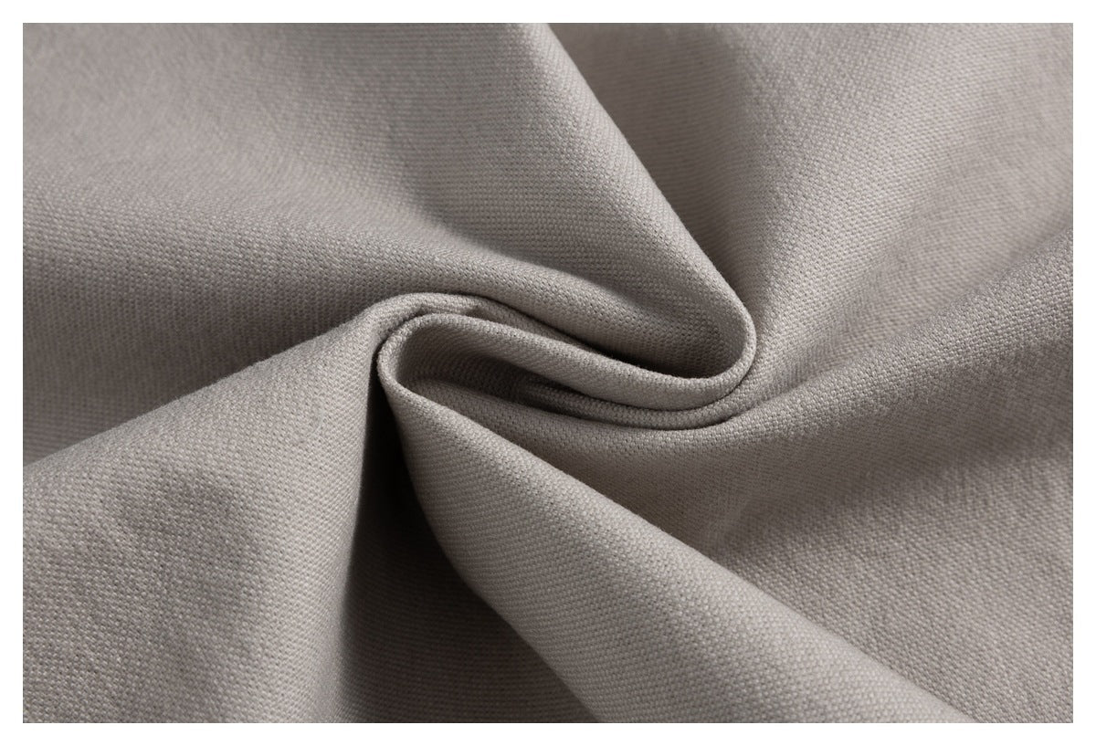 Close-up of light gray woven fabric arranged in soft folds, showing its textured surface.