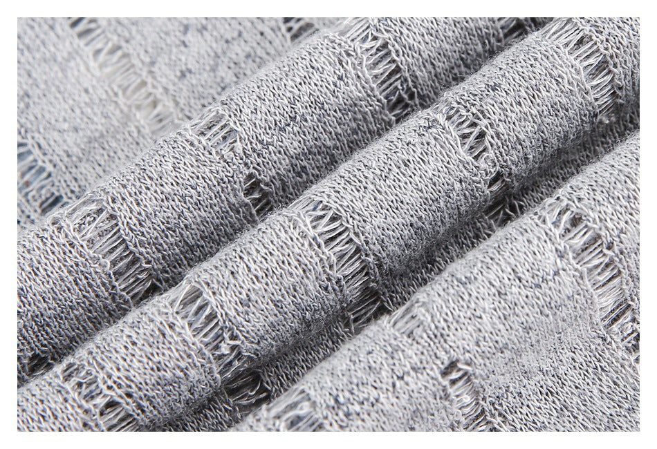 Extreme close-up of gray knit fabric showing a textured, ladder-like open stitch.