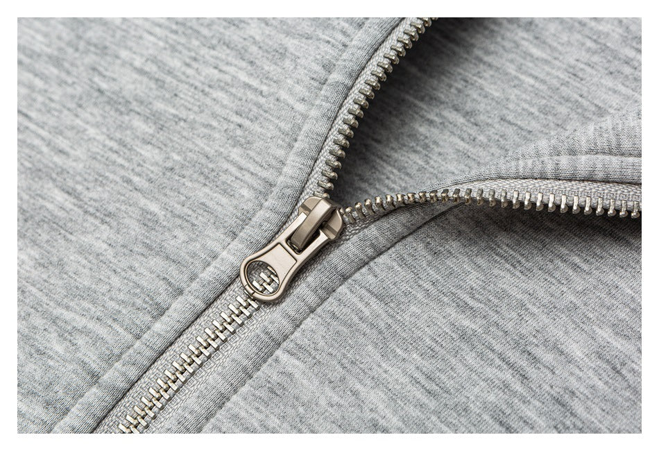 Close-up of a metal zipper and stitching on a light gray heathered garment.