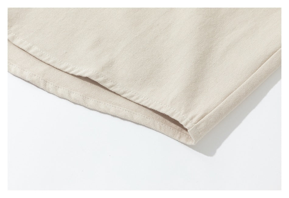 Close-up of the stitched hem on a cream shirt against a white background.