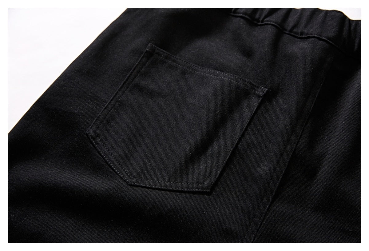 Close-up of a pentagonal patch pocket and stitching on black trousers.