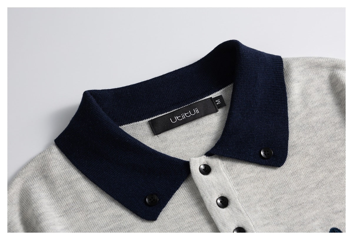 Close-up of a light gray knit polo with a navy collar, black buttons, and a sewn neck label.