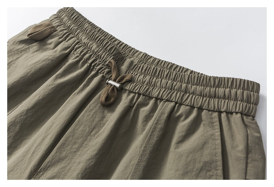 Close-up of the shorts' gathered waistband, brown drawcord, and front stitching.