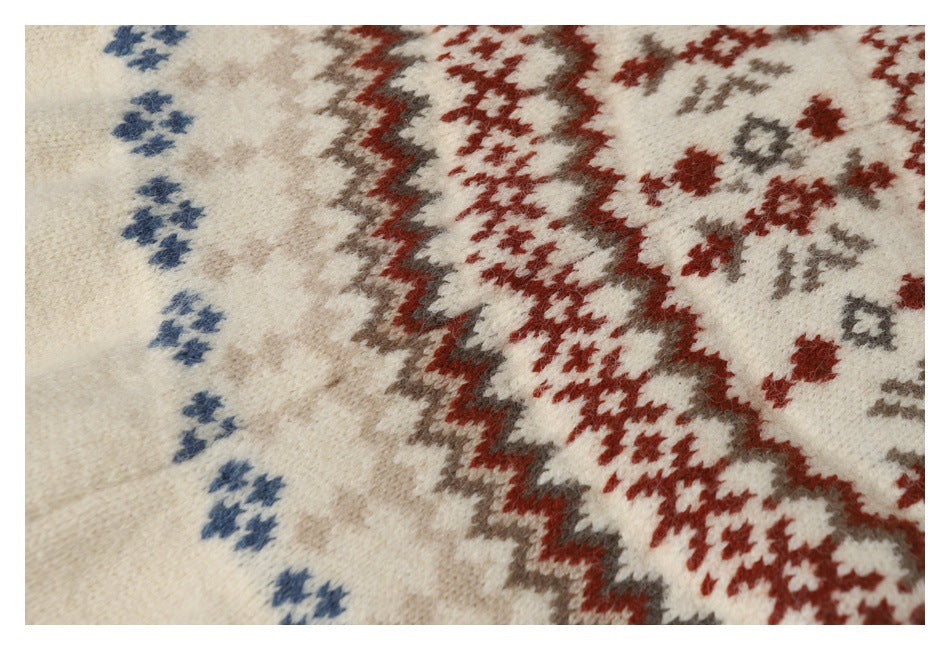Close-up of cream knit fabric with red, gray, and blue geometric motifs.
