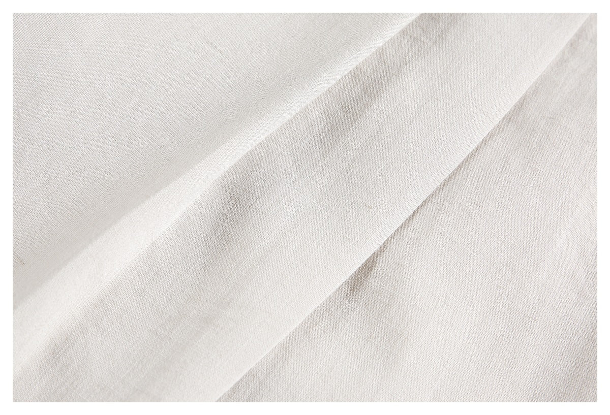 Extreme close-up of ivory trouser fabric and a raised pleat.