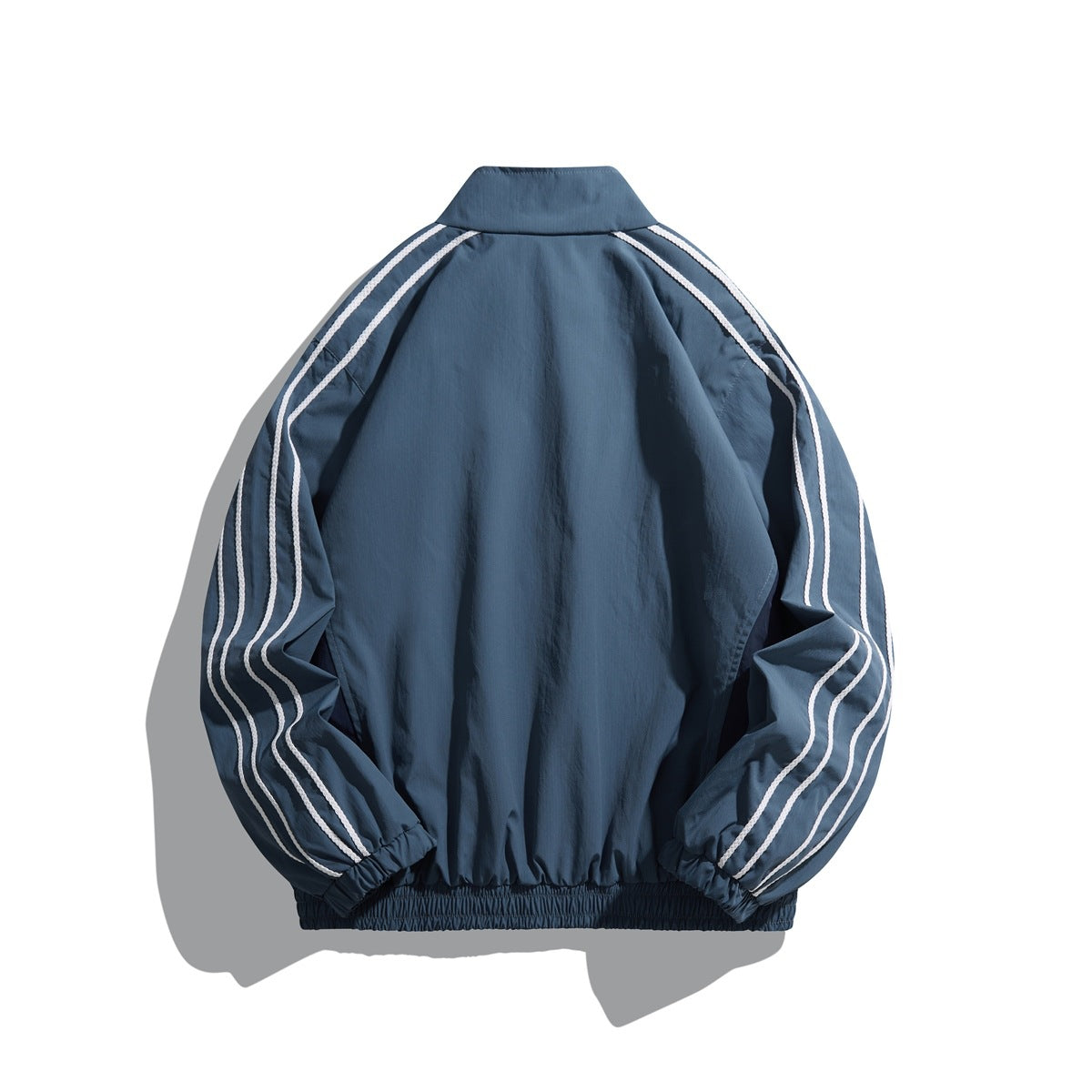 Back view of a slate-blue track jacket with white double sleeve stripes, elastic cuffs and hem.