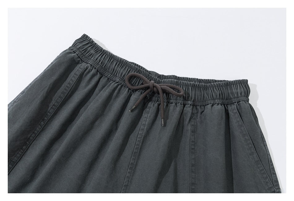 Close-up of charcoal shorts showing the elastic waistband, dark drawstring, and angled front pockets.