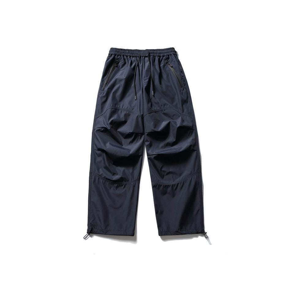 Front view of navy jogger pants with an elastic drawstring waist, zippered pockets, paneled knees, and cuff loops.