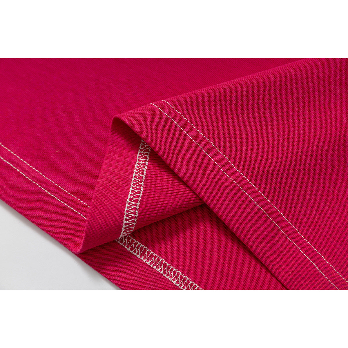 Close-up of the magenta T-shirt’s folded hem and white overlock stitching.