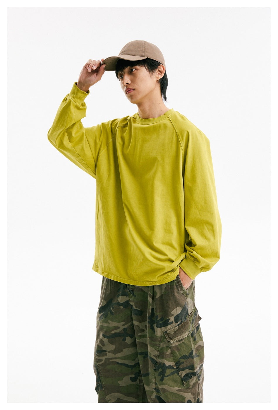 Closer view of a model wearing a bright yellow-green oversized long-sleeve raglan shirt with a crew neck.