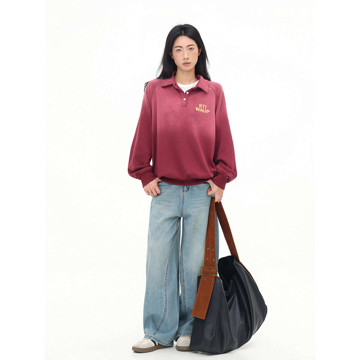 Full-length front view of a model in a rose-red collared pullover with yellow chest lettering and wide-leg light blue jeans.