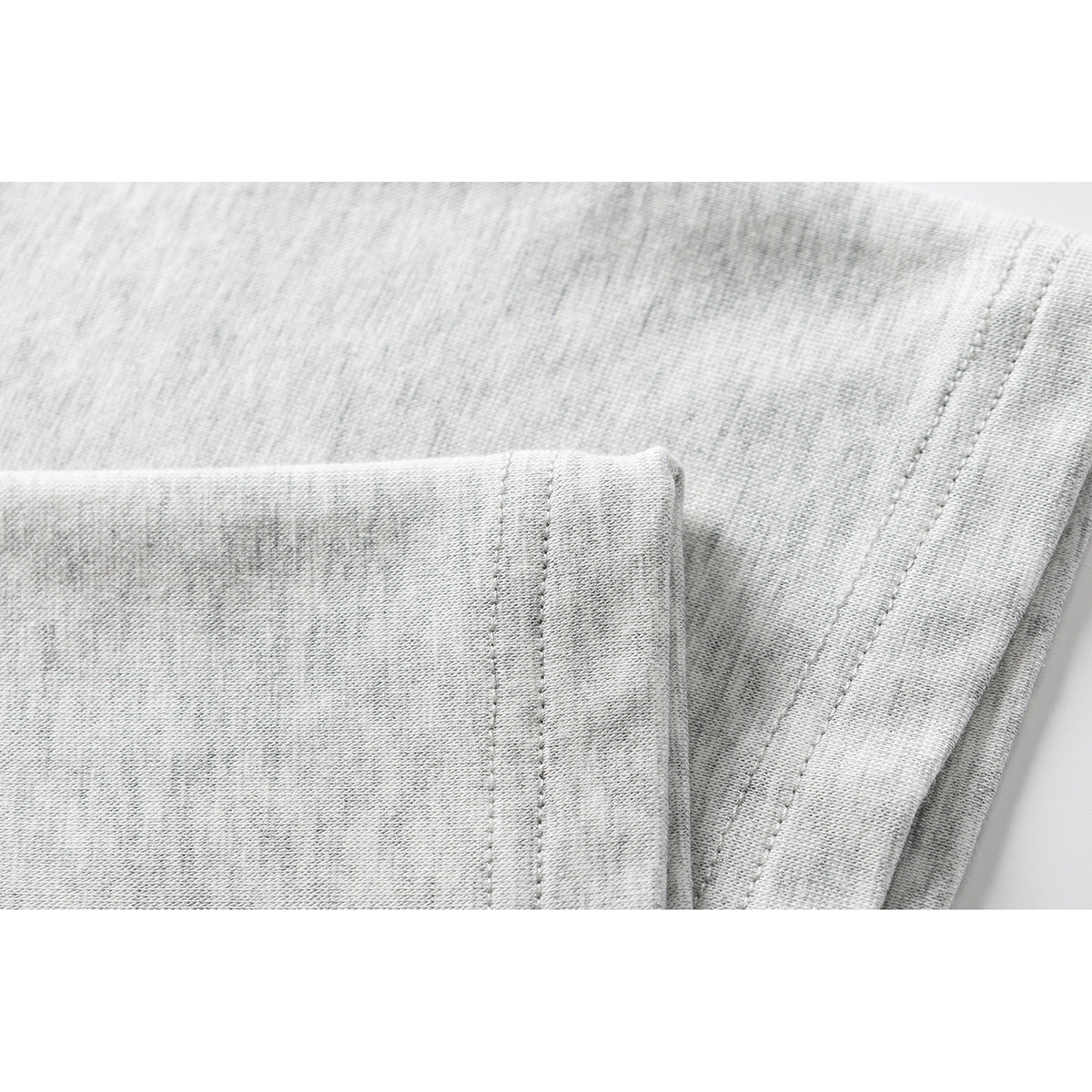 Close-up of light gray knit fabric with a folded, stitched hem.