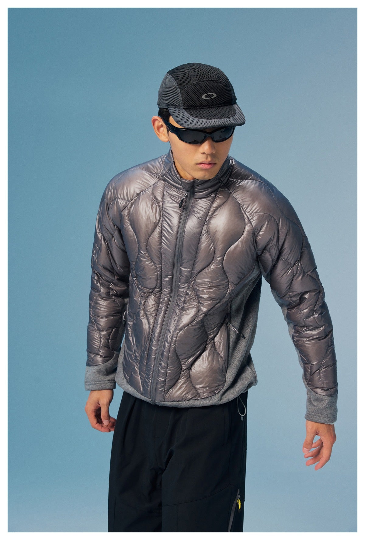 Model leans forward in a charcoal quilted zip jacket with gray side panels and cuffs.