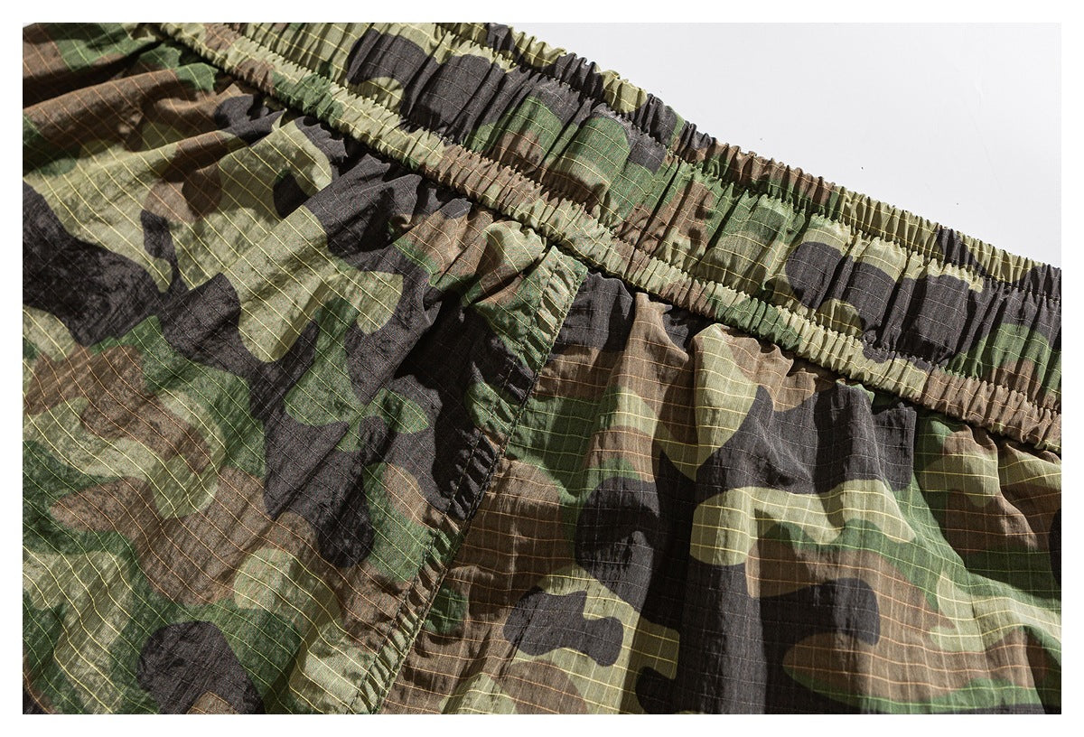 Close-up of camouflage shorts showing the gathered elastic waistband and a stitched pocket.