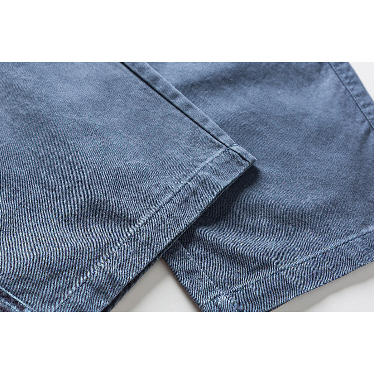 Close-up of the stitched hems on blue pants.