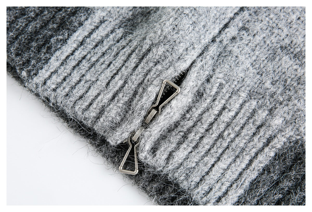 Close-up of a gray marled knit garment edge with ribbing and two metal hook fasteners.