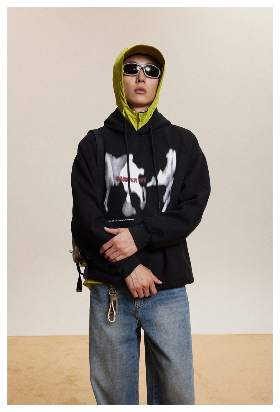 Front view of a person wearing a black hoodie with a white abstract graphic over a neon yellow hooded layer.