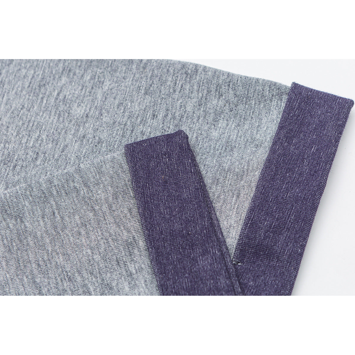 Close-up of a gray melange T-shirt sleeve with a dark purple cuff band.