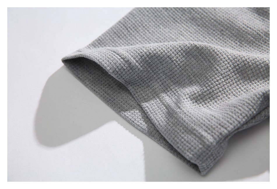 Close-up of the folded sleeve edge on a light gray textured shirt.