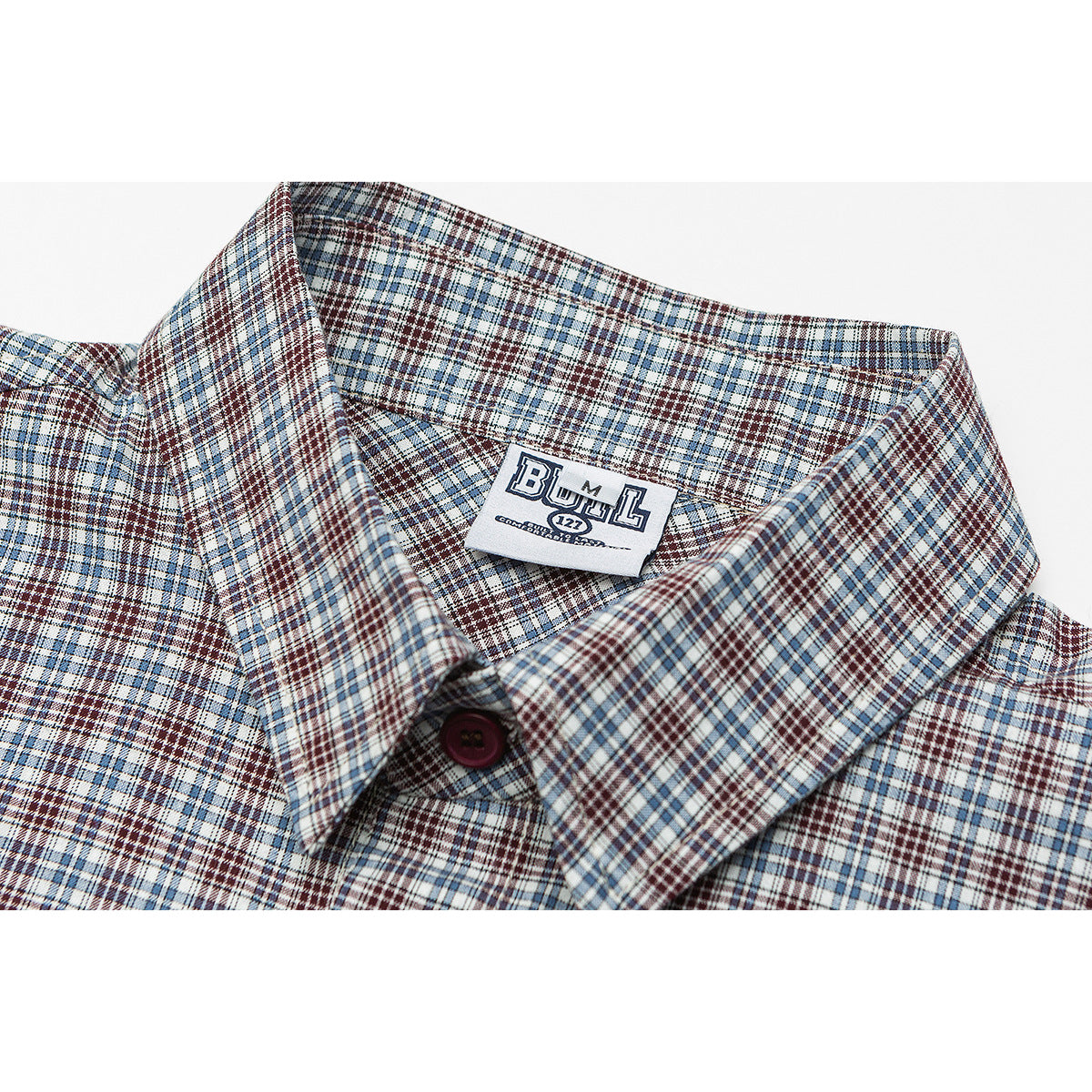 Close-up of a plaid shirt collar, button, and sewn-in BULL neck label.