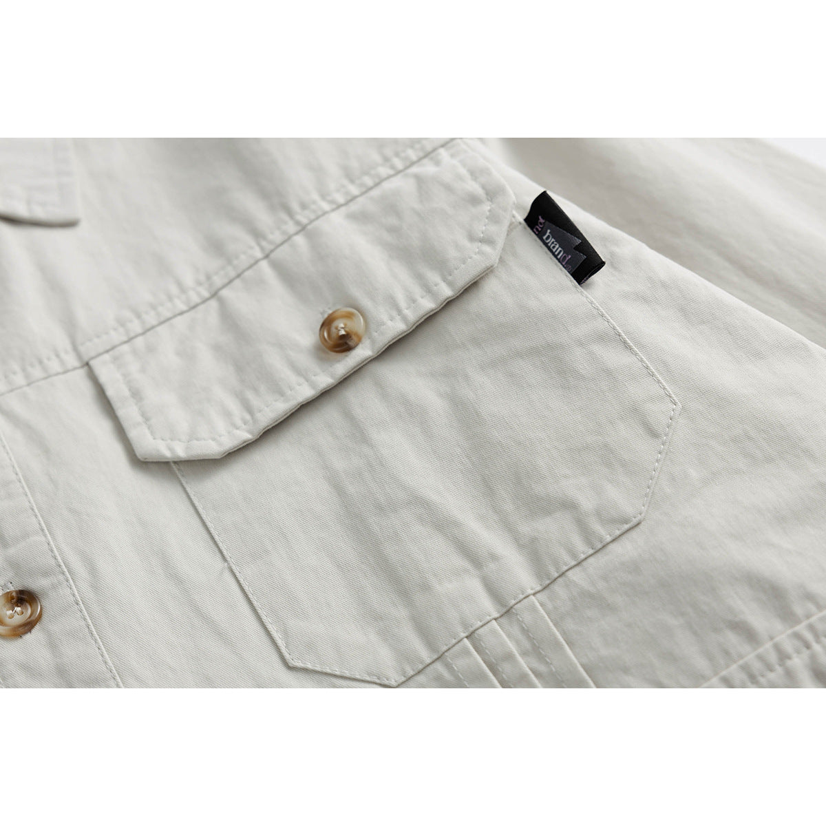 Close-up of an off-white shirt's buttoned chest pocket and a small sewn-in tag.