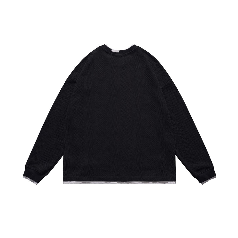 Back view of a black long-sleeve crewneck top with a textured finish, ribbed cuffs, and a white layer peeking below.