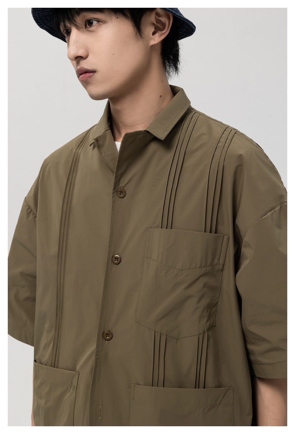 Close-up of the olive-brown shirt's collar, buttons, chest pocket, and vertical stitched details.