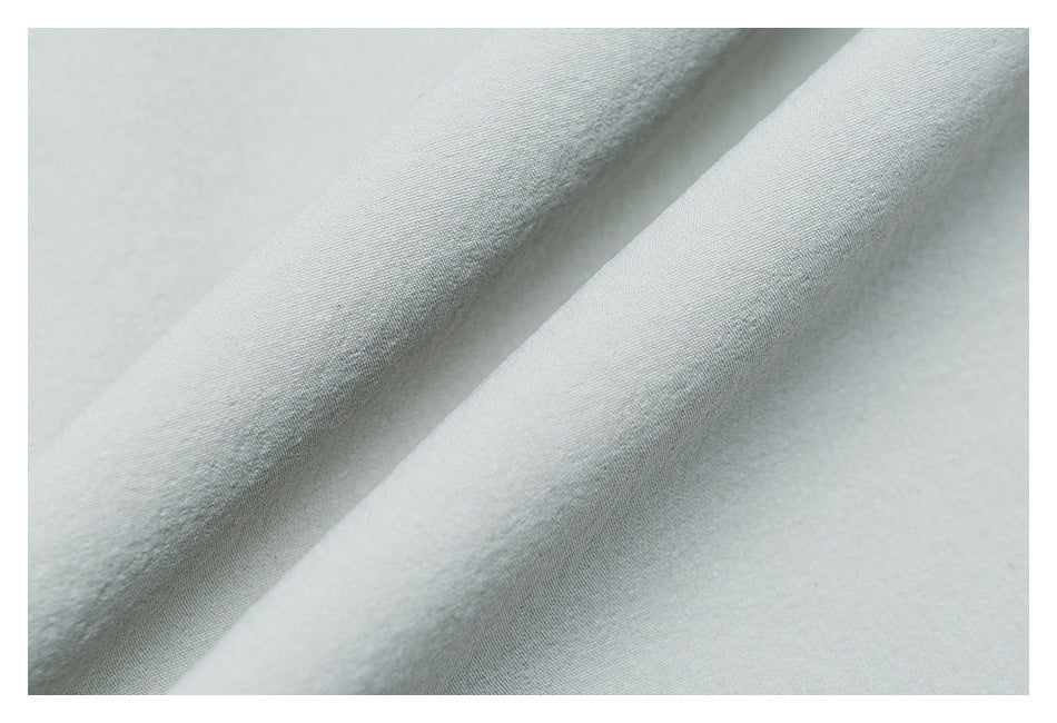 Close-up showing the fine texture of pale gray garment fabric folded into soft ridges.