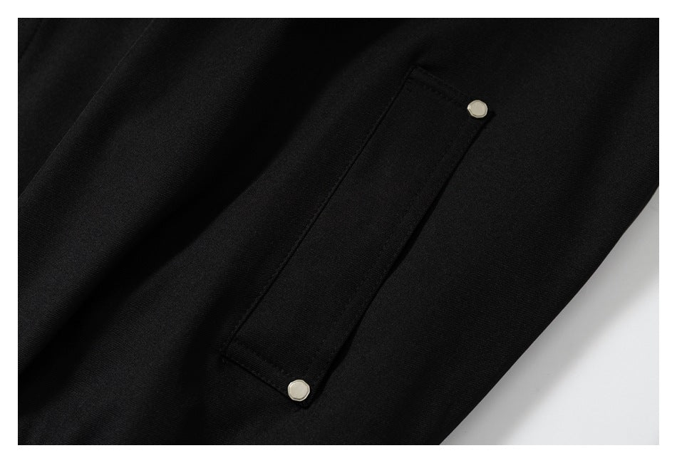 Close-up of a narrow pocket on the black jacket, secured with two small metal snaps.