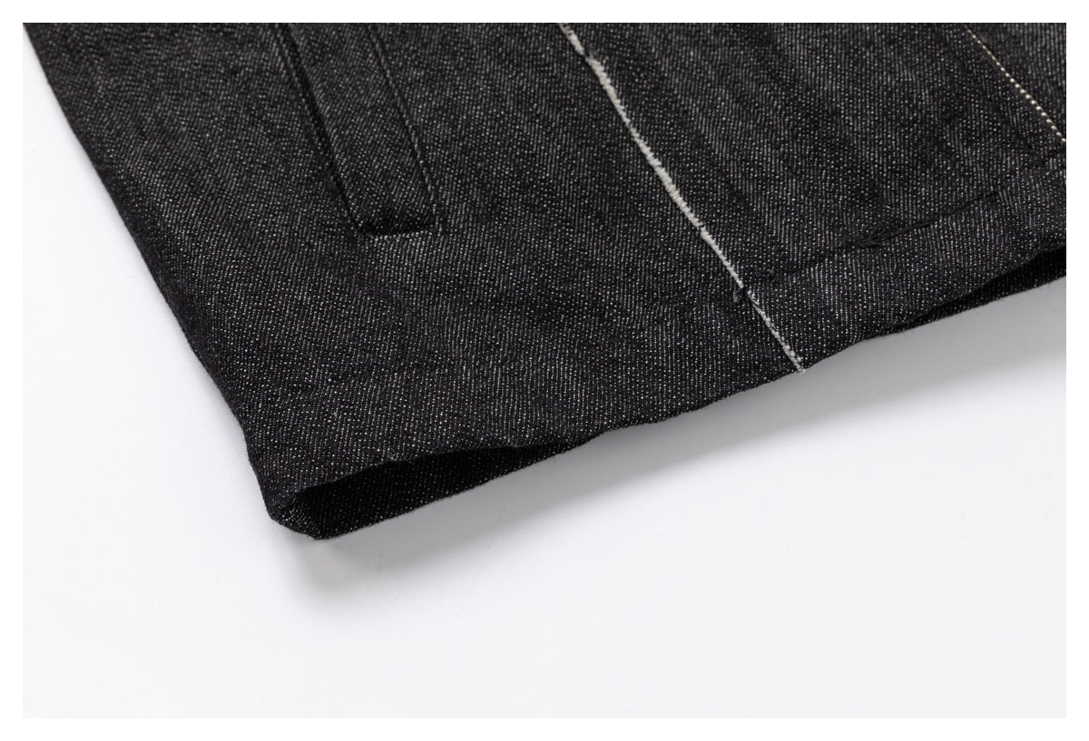 Close-up of the black denim garment's finished hem and pale frayed seam detail.