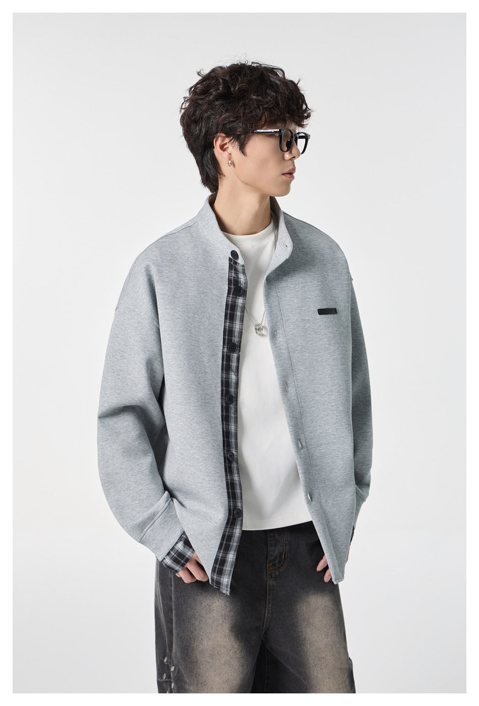 Model in a light gray stand-collar jacket with plaid inner placket and cuffs, shown from a three-quarter angle.