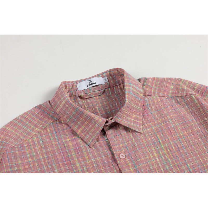 Close-up of a pink plaid button-up shirt collar, shoulder and upper chest with a small neck label.
