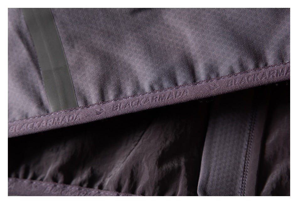 Close-up of a charcoal jacket hem with repeated BLACKARMADA lettering on the binding.