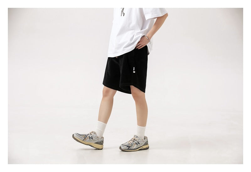Side view of a model wearing loose black shorts with a small light-colored side tab.