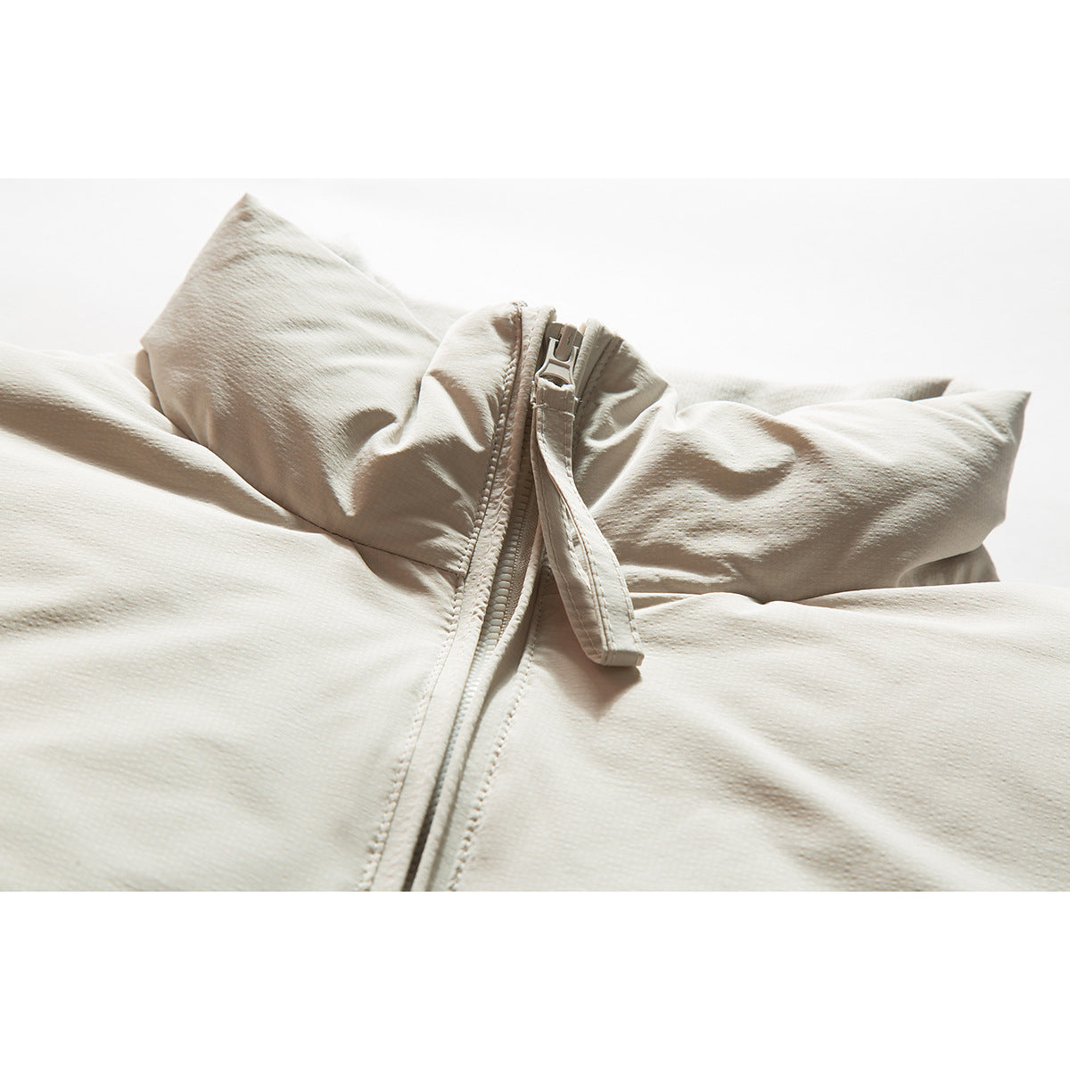 Close-up of an off-white jacket collar and central zipper with a long fabric pull tab.