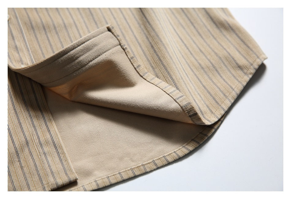 Close-up of the inside and stitched edge of a beige shirt with fine dark vertical stripes.