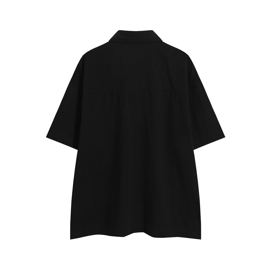 Back view of a loose black short-sleeve collared shirt on a white background.
