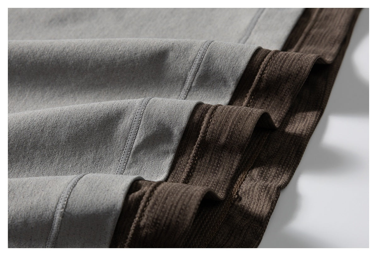 Close-up of gray fabric with stitched edges beside dark brown textured fabric.
