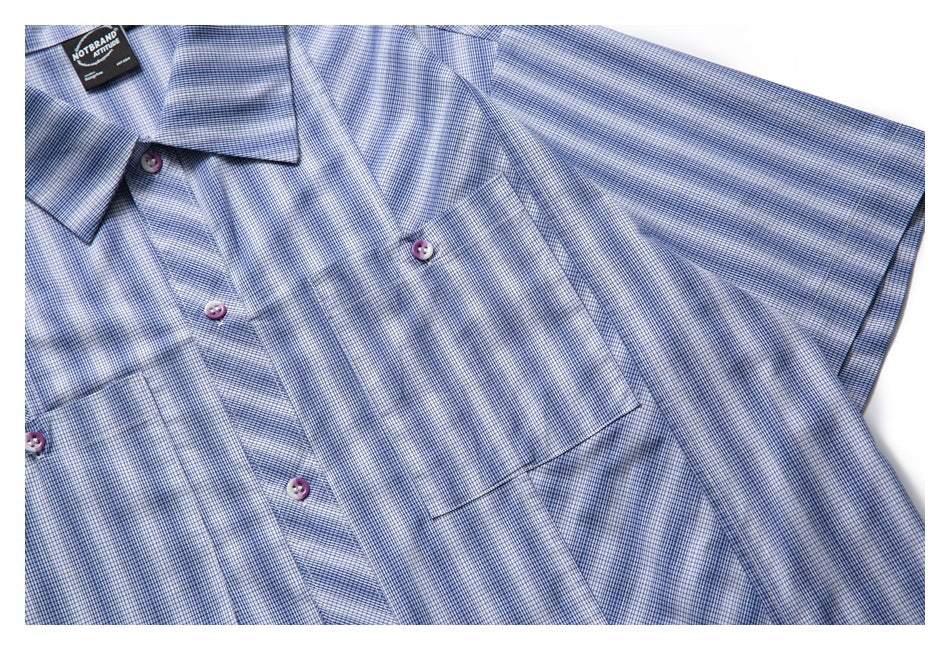 Close view of the blue-and-white checked shirt front, chest pocket, button placket, and extended sleeve.