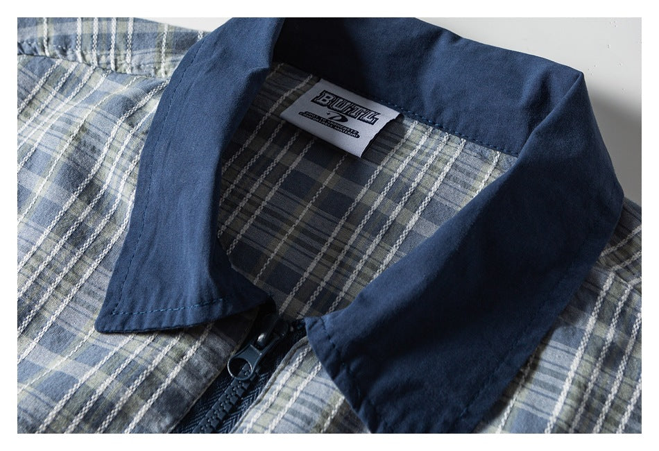 Close-up of a navy collar and black zipper on a blue-gray plaid shirt, with a sewn-in neck label.