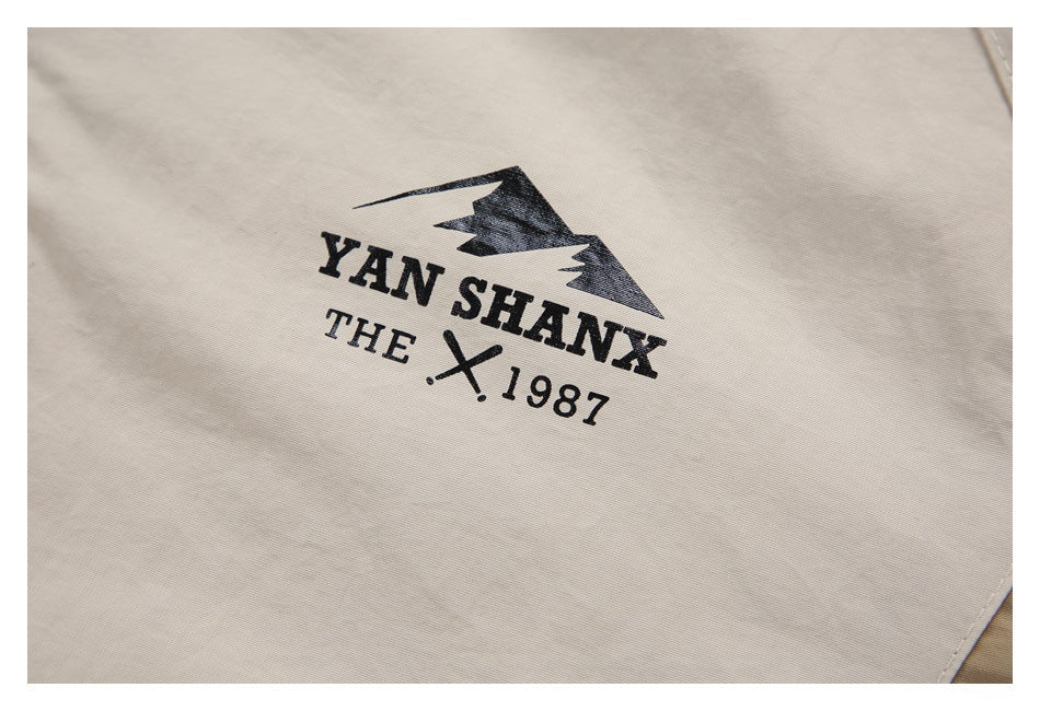 Close-up of a black mountain-style graphic and English lettering printed on light beige jacket fabric.