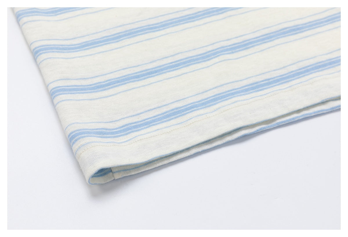 Close-up of a folded edge on off-white fabric with pale blue stripes.